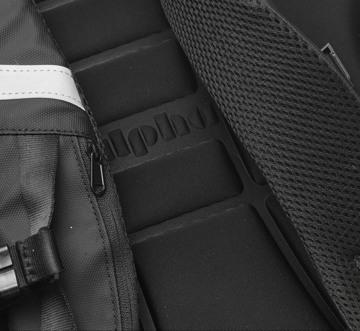 Close-up of a shirt-shaped backpack with a textured back panel and mesh shoulder strap.